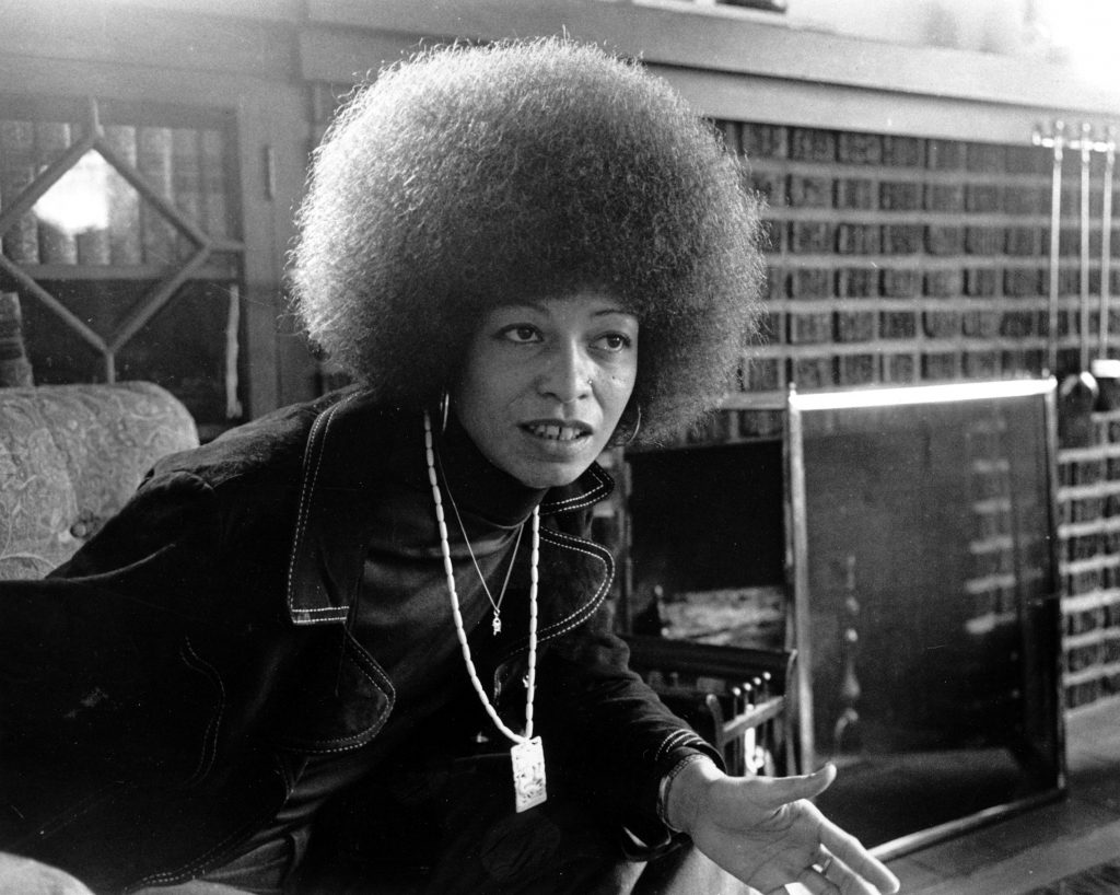 Black militant Angela Davis is seen at home in East Oakland, Calif. on Sept. 9, 1974. She wears two chains representing her commitment to struggle. One is gold, with the hammer and sickle of the Communist Party. The other is ivory with a dragon, ancient symbol of strength and harbinger of revolution. (AP Photo/stf)