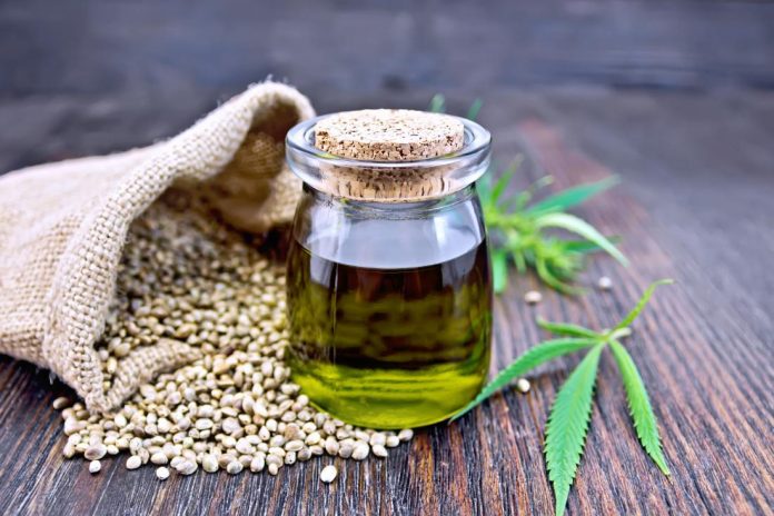 hemp-oil-in-glass-bottle-next-to-hemp-seeds-and-leaves-on-wooden-table