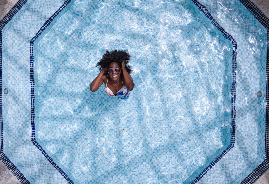Aerial Photo of Woman Wearing White and Blue Bikini Top Standing on Swimming Pool